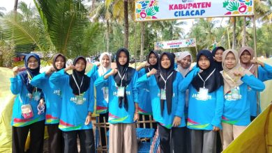 Sekelompok siswi berhijab berpose di depan gerbang tenda "KABUPATEN CILACAP" saat Jambore di pantai.