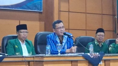Pembicara utama mengenakan kemeja lurik biru sedang berbicara menggunakan mikrofon dalam rapat kerja pengembangan pendidikan Muhammadiyah Magelang.