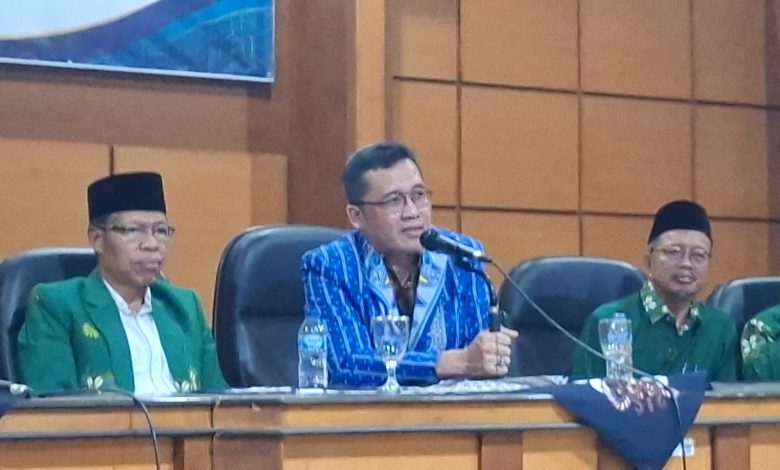 Pembicara utama mengenakan kemeja lurik biru sedang berbicara menggunakan mikrofon dalam rapat kerja pengembangan pendidikan Muhammadiyah Magelang.