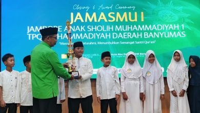 Santri TPQ Nur Hidayah Tanjung berpose bangga dengan piala Juara Umum di panggung Closing Ceremony JamasMu I Banyumas, bersama pembina dan latar belakang layar LED besar.