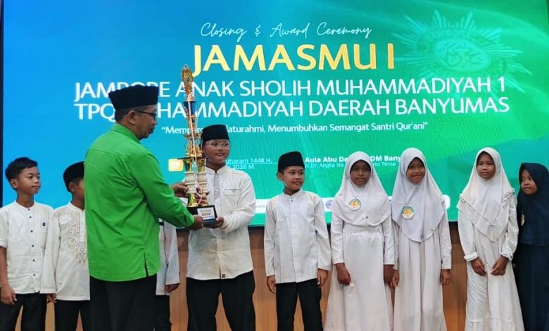 Santri TPQ Nur Hidayah Tanjung berpose bangga dengan piala Juara Umum di panggung Closing Ceremony JamasMu I Banyumas, bersama pembina dan latar belakang layar LED besar.