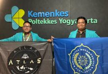 Dua mahasiswa Universitas Muhammadiyah Surakarta membentangkan bendera almamater dan bendera ATLAS setelah meraih penghargaan riset ilmiah.