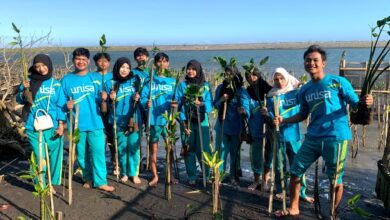 Sekelompok mahasiswa Universitas 'Aisyiyah (UNISA) Yogyakarta mengenakan kaus biru memegang bibit mangrove saat melakukan aksi penanaman di kawasan pesisir Pantai Baros Bantul untuk hadapi krisis iklim.