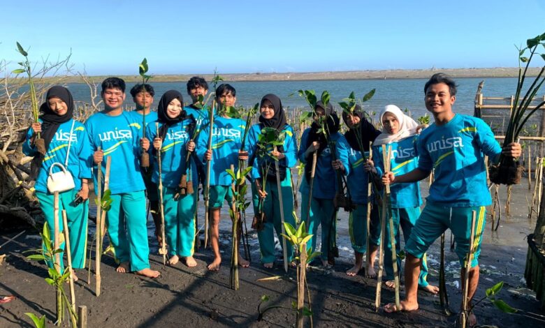 Sekelompok mahasiswa Universitas 'Aisyiyah (UNISA) Yogyakarta mengenakan kaus biru memegang bibit mangrove saat melakukan aksi penanaman di kawasan pesisir Pantai Baros Bantul untuk hadapi krisis iklim.
