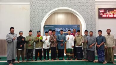 Sekelompok pria mengenakan baju koko dan sarung berfoto bersama dengan gaya jempol di depan spanduk acara Kuliah Subuh.