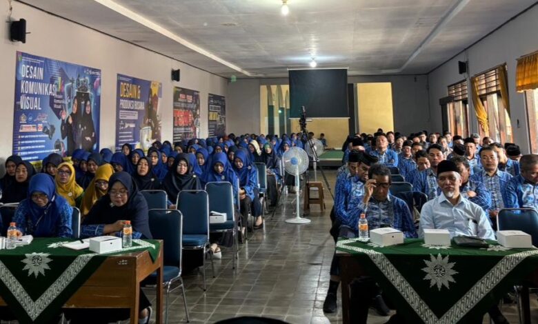 Peserta seminar yang terdiri dari bapak-bapak dan ibu-ibu dengan seragam biru sedang duduk rapi menyimak acara di dalam ruangan aula.