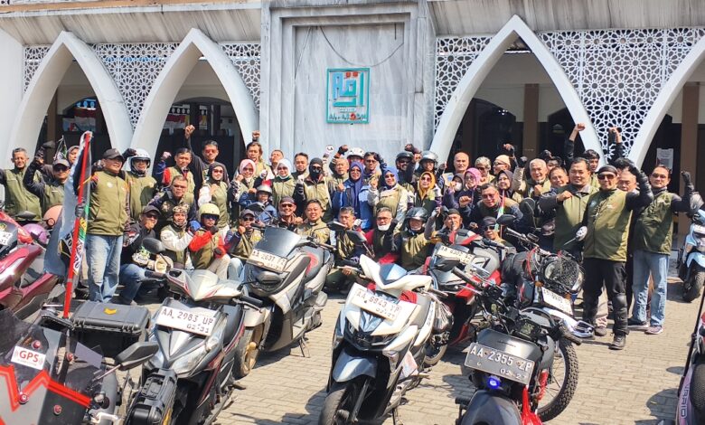 Sekelompok anggota komunitas motor dengan rompi seragam berfoto bersama di depan Masjid Al-Aqom dengan sepeda motor mereka.