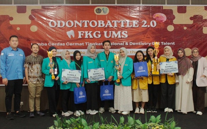 Para pemenang kompetisi cerdas cermat mahasiswa kedokteran gigi Odontobattle 2.0 FKG UMS berfoto bersama panitia dan dewan juri di atas panggung sambil memegang piala serta hadiah simbolis.