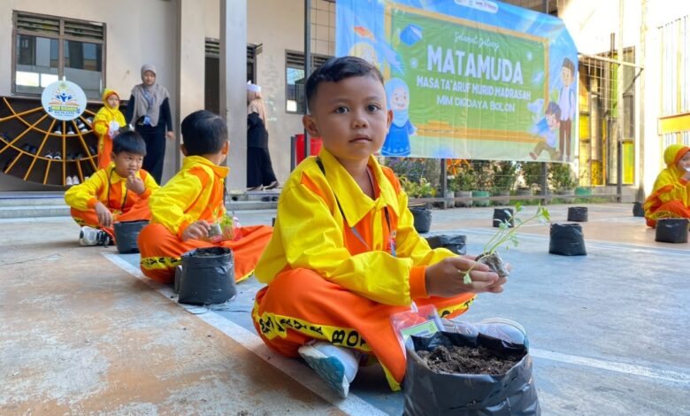 Murid baru memegang bibit sayuran saat mengikuti Masa Pengenalan Lingkungan Sekolah di MIM Digdaya Bolon.