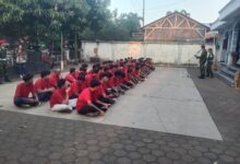 Seorang instruktur senior berbaju merah sedang memberikan arahan langsung kepada peserta Diklatsar Kokam 2026.