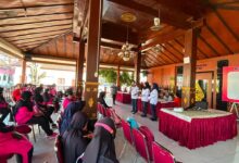 Mahasiswa UMS sedang memberikan pemaparan materi mengenai kesehatan kepada peserta program PROLANIS di area terbuka.