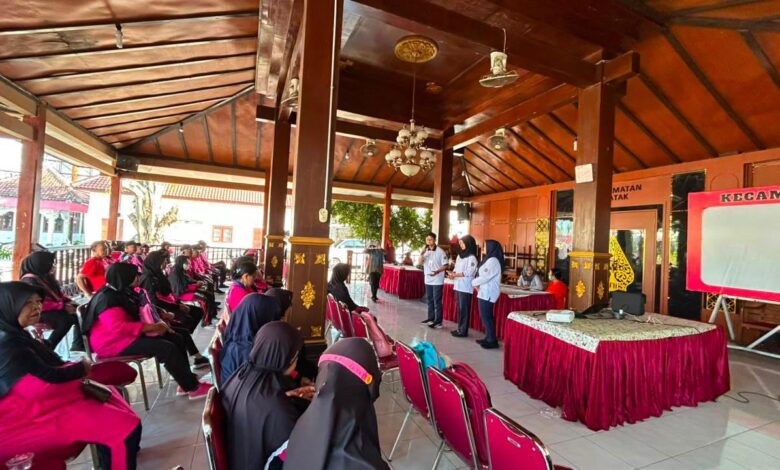 Mahasiswa UMS sedang memberikan pemaparan materi mengenai kesehatan kepada peserta program PROLANIS di area terbuka.