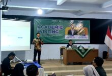 Narasumber sedang memberikan materi dalam workshop Academic Writing UMBS di depan spanduk bertuliskan "ACADEMIC WRITING: Strategi Menulis Artikel Ilmiah Berkualitas menuju Jurnal Bereputasi".
