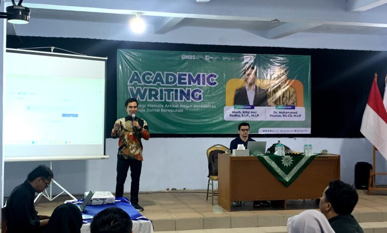 Narasumber sedang memberikan materi dalam workshop Academic Writing UMBS di depan spanduk bertuliskan "ACADEMIC WRITING: Strategi Menulis Artikel Ilmiah Berkualitas menuju Jurnal Bereputasi".