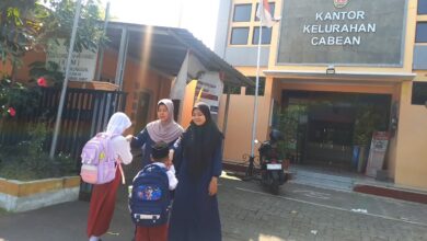 Dua orang guru menyambut siswa SD Muhammadiyah Semarang yang membawa tas ransel di halaman depan Kantor Kelurahan Cabean Semarang Barat.