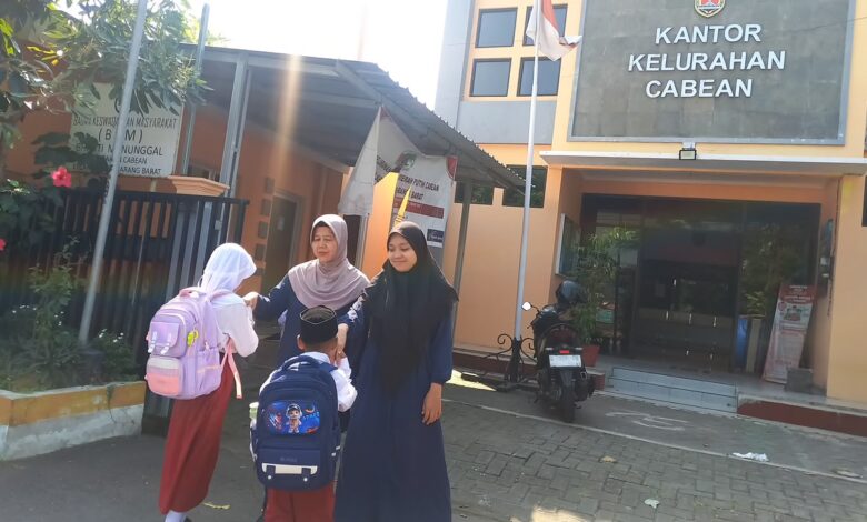 Dua orang guru menyambut siswa SD Muhammadiyah Semarang yang membawa tas ransel di halaman depan Kantor Kelurahan Cabean Semarang Barat.