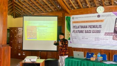 Seorang pemateri sedang menjelaskan teknik menulis feature di depan proyektor saat pelatihan bagi guru.