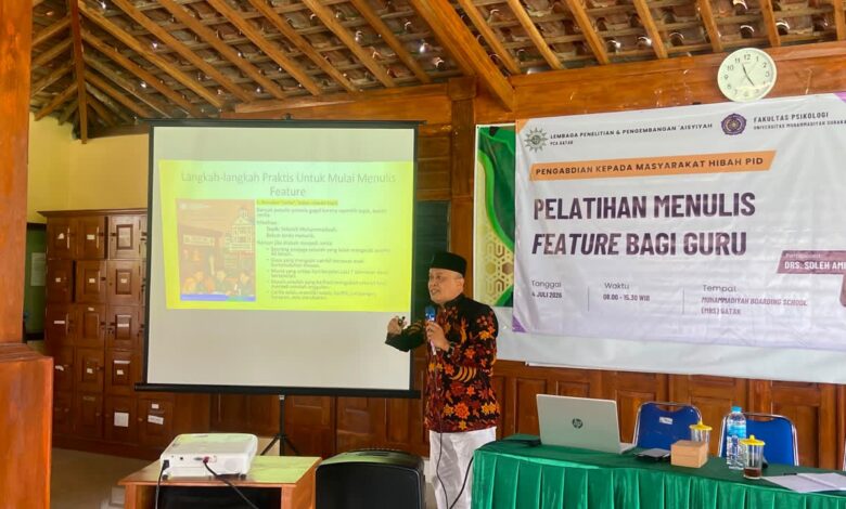 Seorang pemateri sedang menjelaskan teknik menulis feature di depan proyektor saat pelatihan bagi guru.