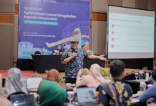 Dr. Budi Santoso memaparkan materi penulisan berita dalam Workshop Pengabdian Masyarakat UMS di hadapan peserta. Di latar belakang terlihat banner workshop dan layar proyektor dengan poin Anatomi Berita.