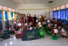 Anggota BikersMu Chapter Banggai berfoto bersama anak-anak sekolah pedalaman Tobiombong yang memegang buku bantuan.