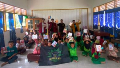 Anggota BikersMu Chapter Banggai berfoto bersama anak-anak sekolah pedalaman Tobiombong yang memegang buku bantuan.