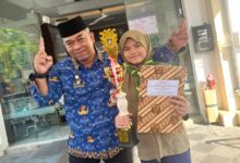 Tabina Khansa Nirwasita berfoto bersama gurunya sambil memegang piala juara 1 lomba menulis cerita.