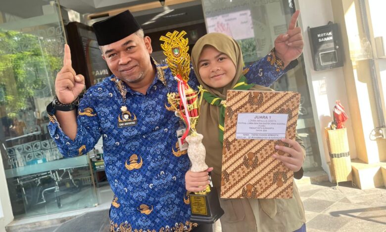 Tabina Khansa Nirwasita berfoto bersama gurunya sambil memegang piala juara 1 lomba menulis cerita.