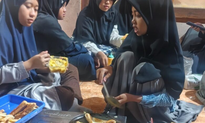 Sekelompok santri putri berhijab di Pondok Pesantren Muhammadiyah Manafi'ul Ulum Sambi berkolaborasi membuat pizza mini di wajan sebagai bagian dari praktik santri belajar bisnis kuliner.