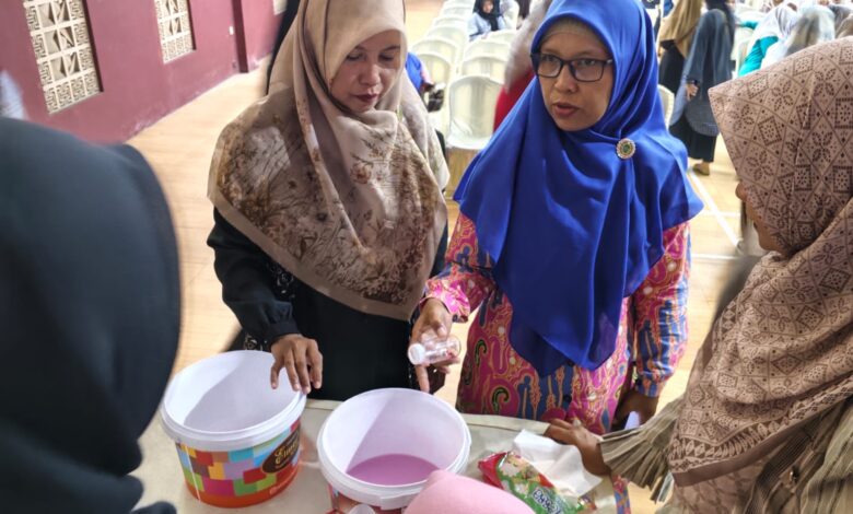 Seorang instruktur perempuan berjilbab biru memberikan demonstrasi praktis pembuatan softener kepada peserta pelatihan wirausaha.