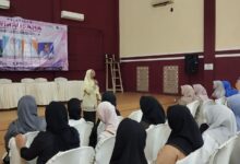 Seorang narasumber sedang memberikan materi pelatihan wirausaha pembuatan softener kepada audiens perempuan di dalam aula pertemuan.
