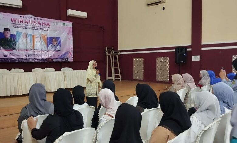 Seorang narasumber sedang memberikan materi pelatihan wirausaha pembuatan softener kepada audiens perempuan di dalam aula pertemuan.