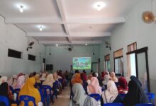 Seorang pembicara sedang memaparkan materi tentang pendidikan anak di depan audiens dalam sebuah seminar parenting di aula masjid.