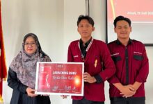 Wakil Dekan II FAI UMP Ibu Istianah bersama kader IMM UMP memegang papan pengumuman peluncuran Buku Nyala Obor Kader dalam acara Musykom di Purwokerto.