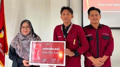Wakil Dekan II FAI UMP Ibu Istianah bersama kader IMM UMP memegang papan pengumuman peluncuran Buku Nyala Obor Kader dalam acara Musykom di Purwokerto.