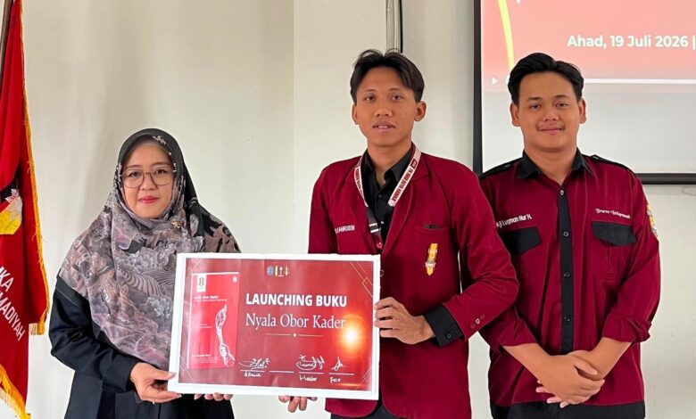 Wakil Dekan II FAI UMP Ibu Istianah bersama kader IMM UMP memegang papan pengumuman peluncuran Buku Nyala Obor Kader dalam acara Musykom di Purwokerto.