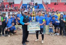 Tim sepak bola berpose bersama membawa piala dan papan simbolis Juara 1 PDM Wonosobo Cup 2026 di lapangan stadion setelah pertandingan final.