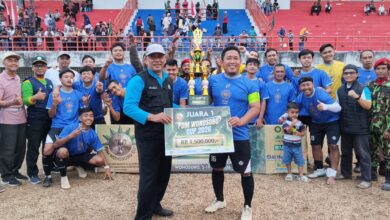 Tim sepak bola berpose bersama membawa piala dan papan simbolis Juara 1 PDM Wonosobo Cup 2026 di lapangan stadion setelah pertandingan final.