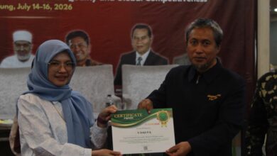 Seorang wanita menyerahkan sertifikat penghargaan "Top Lecturer" kepada seorang pria di atas panggung acara konferensi formal.