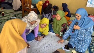 Sekelompok ibu rumah tangga berhijab sedang berdiskusi kelompok (FGD) dan menulis di kertas plano besar dalam acara pelatihan kesehatan mental di Wonogiri.