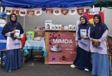 Tiga wanita berhijab memegang brosur pendaftaran siswa baru di depan stan pameran produk kedai kopi lokal MIMDA Coffee milik MI Muhammadiyah Danurejo saat acara Car Free Day di Alun-alun Temanggung.