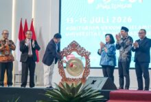 Enam pejabat universitas di atas panggung dalam acara pembukaan, dengan seorang pria memukul gong besar untuk meresmikan acara Lomba Dangdut Peksimida Jateng 2026 di UMP. Di latar belakang terdapat layar LED besar bertuliskan teks acara.
