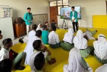 Dua mahasiswa UMS mengenakan almamater hijau memberikan sosialisasi Smart Body Care di hadapan para siswa tunagrahita SLB Negeri Colomadu yang duduk di matras kuning.