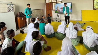 Dua mahasiswa UMS mengenakan almamater hijau memberikan sosialisasi Smart Body Care di hadapan para siswa tunagrahita SLB Negeri Colomadu yang duduk di matras kuning.