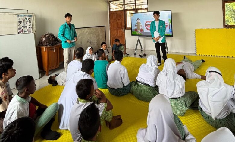 Dua mahasiswa UMS mengenakan almamater hijau memberikan sosialisasi Smart Body Care di hadapan para siswa tunagrahita SLB Negeri Colomadu yang duduk di matras kuning.