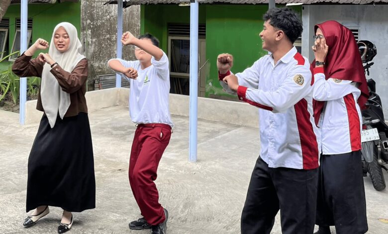 Empat orang, termasuk mahasiswa UNIMMA dan siswa berkebutuhan khusus berhijab, sedang menari bersama di area parkir sekolah.