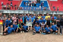 Foto bersama juara pertama Kejuaraan Sepak Bola PDM Wonosobo Piala PSHW di Stadion Gelora Pancasila, berpose dengan piala dan papan hadiah uang tunai Rp1.500.000, dikelilingi ofisial dan penonton di tribun merah-biru.