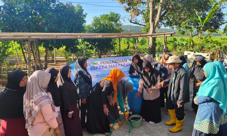 Dosen STEM Cilacap mendampingi ibu-ibu KWT Karangjengkol mempraktikkan cara membuat pupuk organik cair dari limbah kotoran hewan di sebuah tong plastik besar.