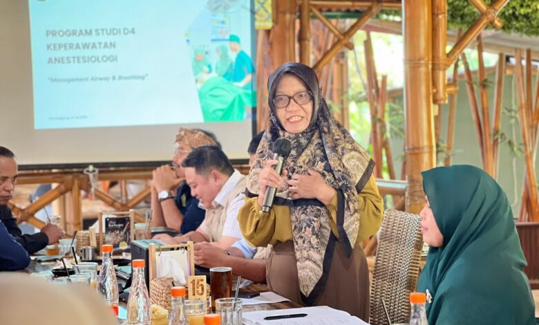 Wakil Direktur II AKMT Min Adadiyah memberikan sambutan dalam acara kolaborasi dengan Penata Anestesi (IPAI) di Temanggung. Di latar belakang terlihat layar proyektor menampilkan logo AKMT dan judul Program Studi D4 Keperawatan Anestesiologi.