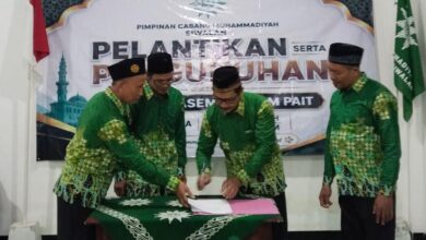 Prosesi penandatanganan berkas pelantikan pengurus Pimpinan Cabang Muhammadiyah (PCM) Siwalan yang disaksikan oleh para pengurus mengenakan seragam hijau batik khas Muhammadiyah.