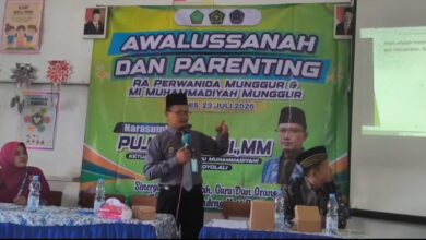 Seorang narasumber berdiri menyampaikan materi di depan banner acara Awalussanah dan Parenting RA Perwanida Munggur serta MI Muhammadiyah Munggur.